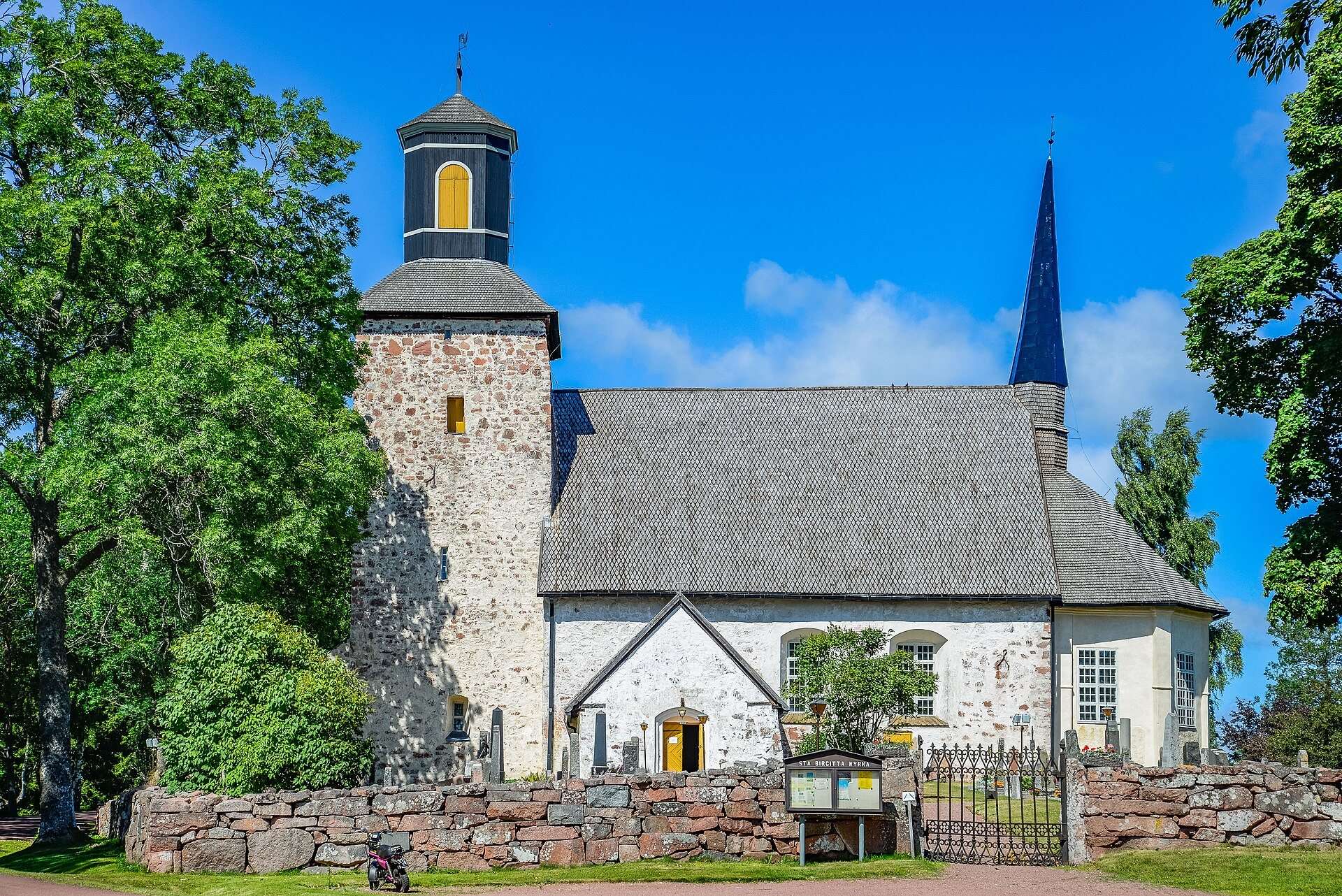 Lemlands kyrka av gråsten i Söderby, med torn och kyrkogårdsmur