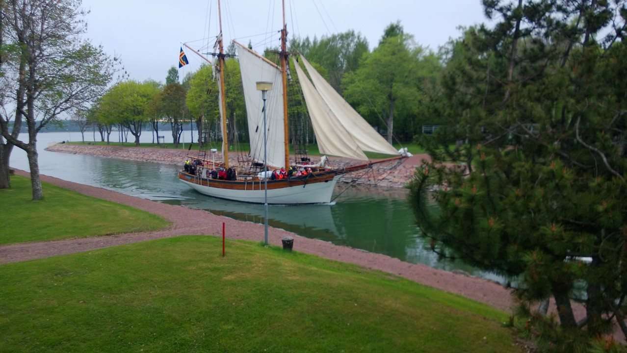 Skuta med segel vid kanalens strand